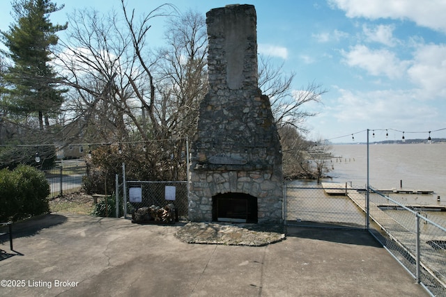 exterior space featuring an outdoor stone fireplace and fence