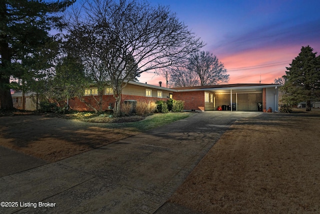 single story home with an attached carport, brick siding, and driveway