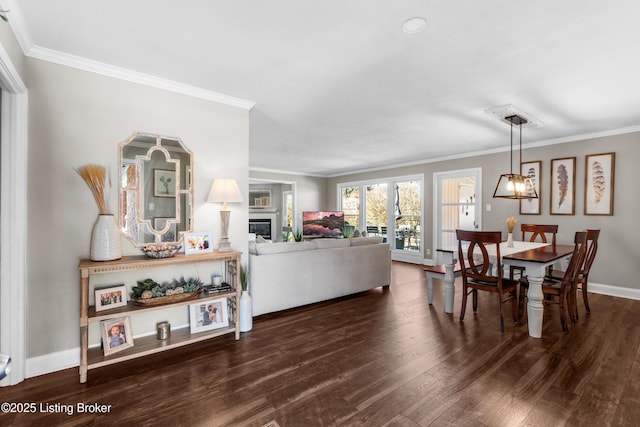 living room featuring crown molding, baseboards, dark wood-style flooring, and a glass covered fireplace