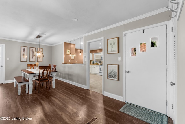 dining space featuring ornamental molding, wood finished floors, and baseboards