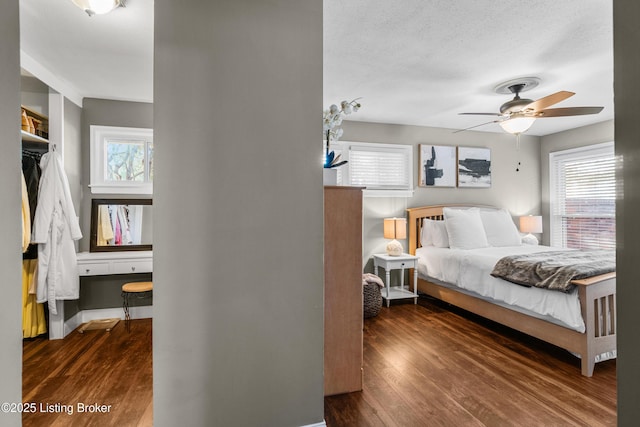 bedroom with a textured ceiling, multiple windows, and dark wood-style flooring