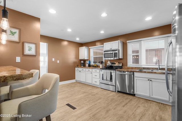 kitchen featuring appliances with stainless steel finishes, white cabinets, and decorative light fixtures