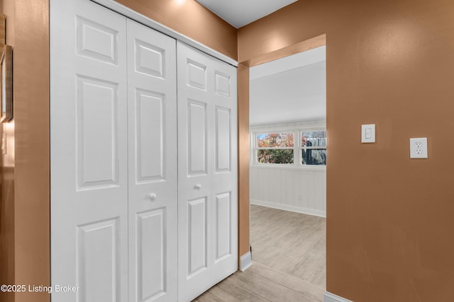 corridor with baseboards and light wood finished floors