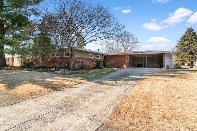 ranch-style home featuring driveway, a front yard, an attached carport, and brick siding