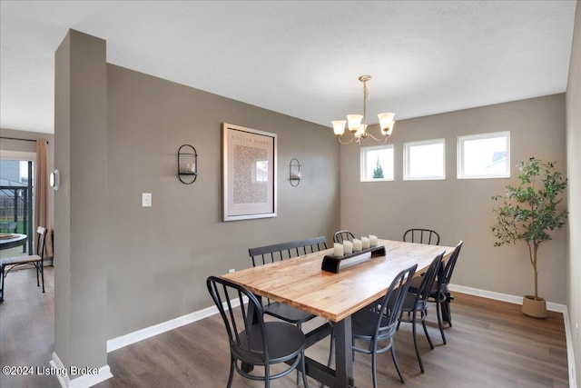 dining space with an inviting chandelier, baseboards, and wood finished floors