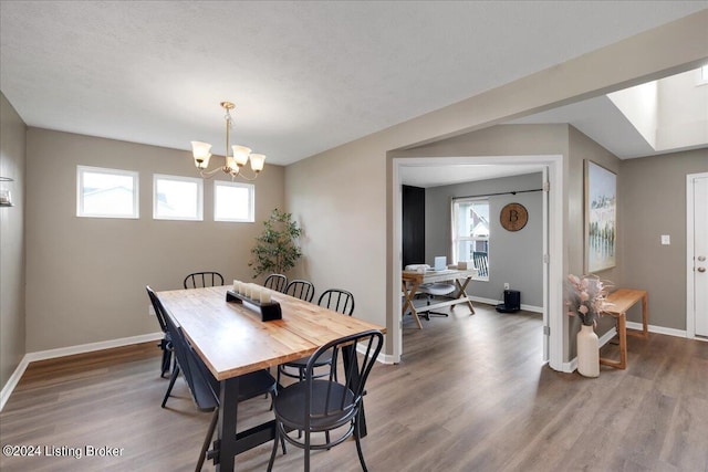 dining room featuring a notable chandelier, plenty of natural light, wood finished floors, and baseboards