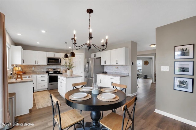 dining room with a notable chandelier, baseboards, wood finished floors, and recessed lighting