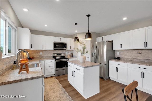 kitchen featuring appliances with stainless steel finishes, white cabinets, a sink, and wood finished floors