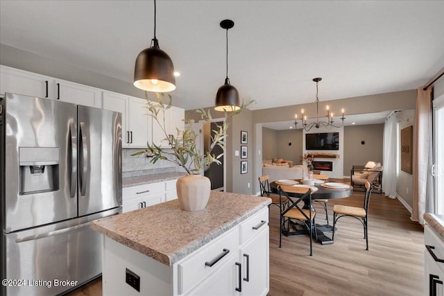 kitchen with light wood-style floors, white cabinetry, hanging light fixtures, and stainless steel refrigerator with ice dispenser