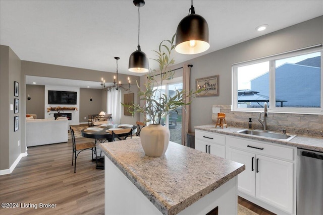 kitchen featuring decorative backsplash, dishwasher, a fireplace, white cabinetry, and a sink