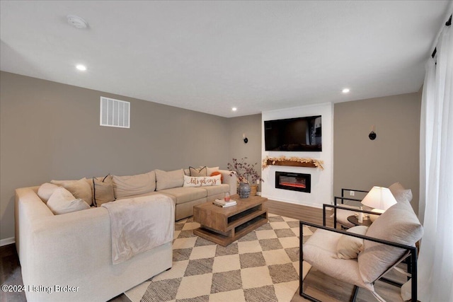 living area with visible vents, baseboards, a glass covered fireplace, light wood-style flooring, and recessed lighting