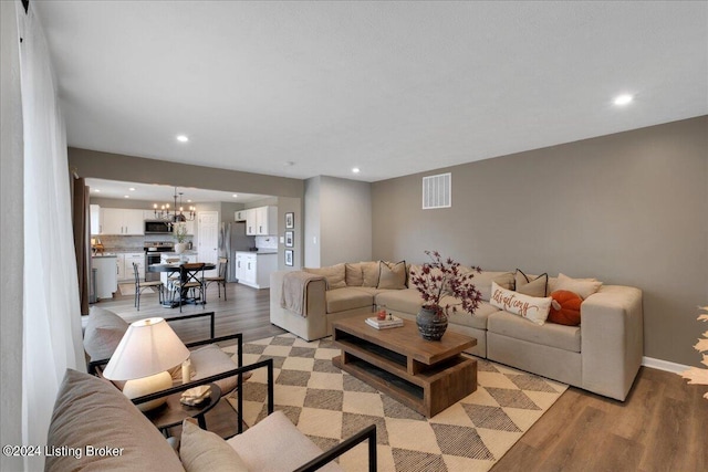 living room featuring light wood-style flooring, visible vents, a notable chandelier, and recessed lighting