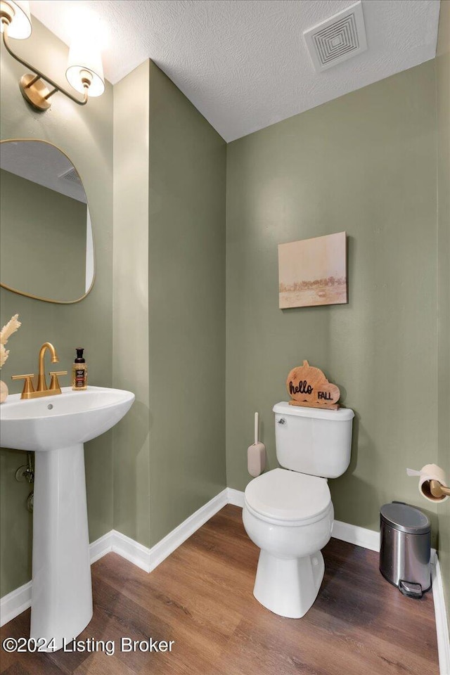 bathroom with visible vents, a textured ceiling, toilet, and wood finished floors