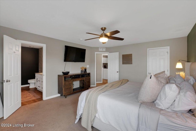 bedroom featuring light carpet, visible vents, baseboards, ceiling fan, and ensuite bathroom