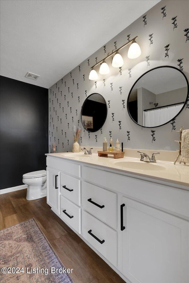 full bath featuring wallpapered walls, visible vents, toilet, wood finished floors, and a sink