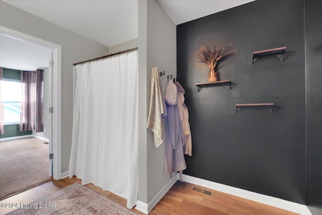 bathroom with a shower with curtain, wood finished floors, visible vents, and baseboards