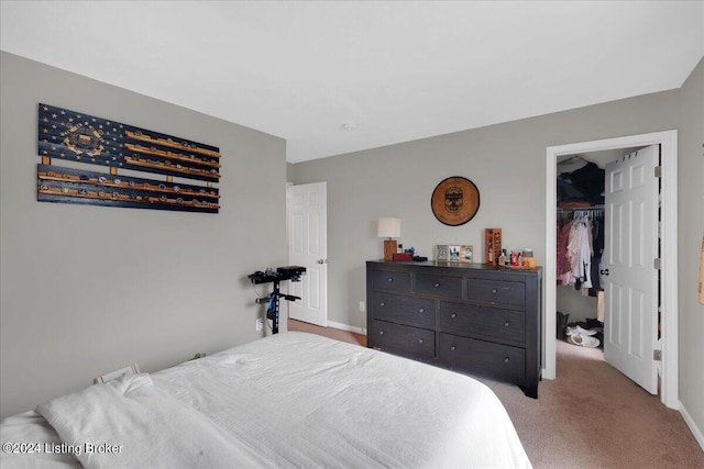 bedroom featuring a closet, light carpet, a spacious closet, and baseboards