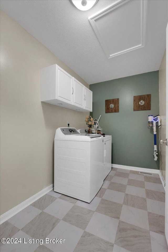 washroom with a textured ceiling, washer and clothes dryer, cabinet space, and baseboards