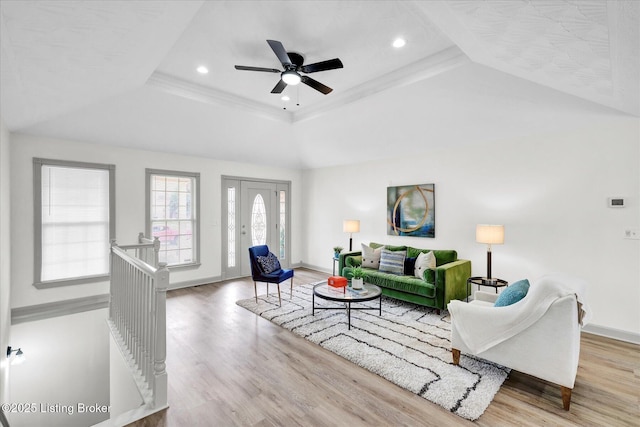 living area with a tray ceiling, wood finished floors, and baseboards