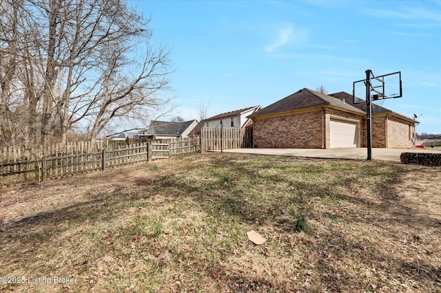 view of home's exterior with a garage, concrete driveway, fence, a yard, and brick siding