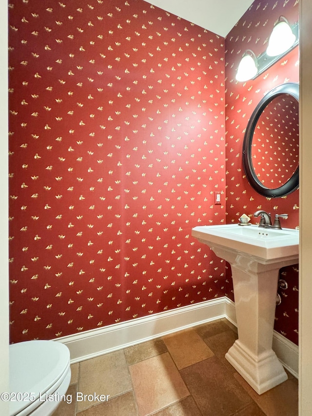 half bath featuring toilet and baseboards