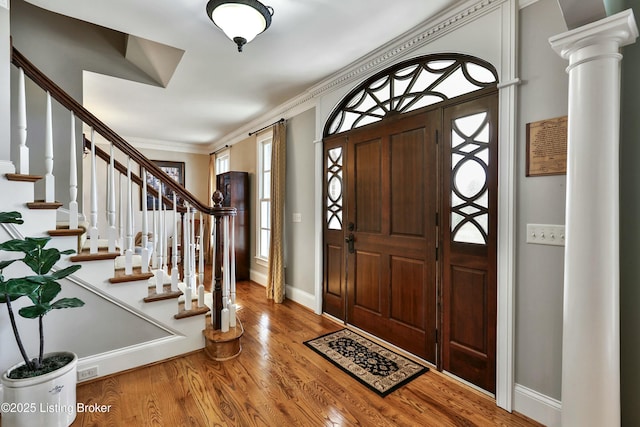 foyer featuring baseboards, stairs, ornamental molding, and wood finished floors