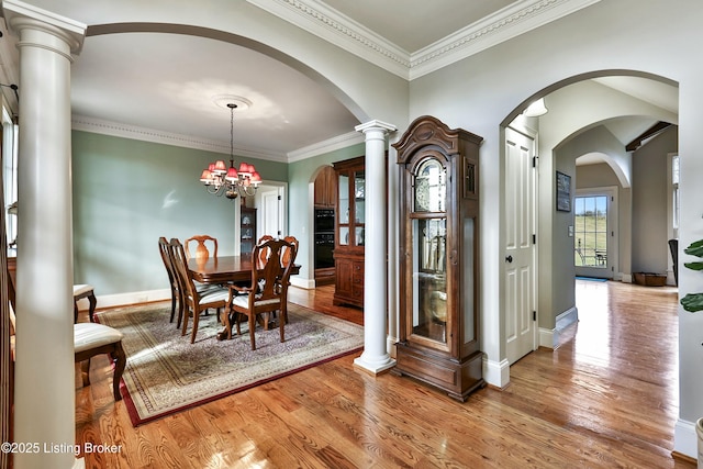 dining area with light wood-style floors, baseboards, a chandelier, and crown molding