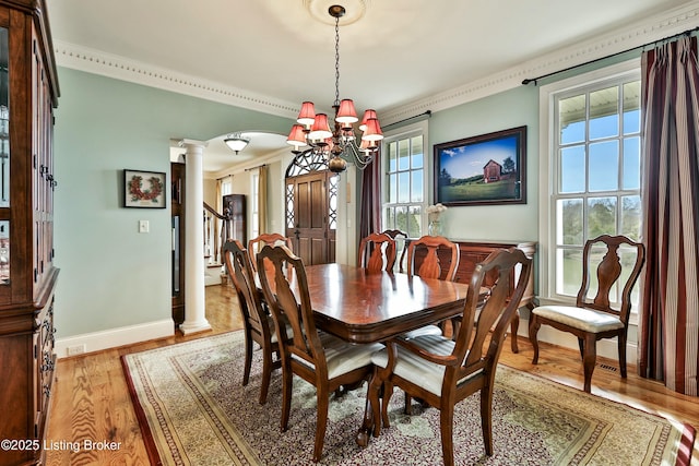 dining space featuring arched walkways, ornate columns, light wood-style flooring, an inviting chandelier, and baseboards