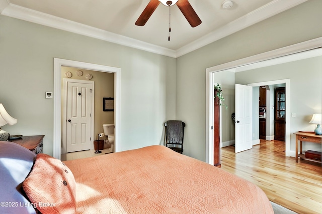 bedroom featuring light wood-style floors, baseboards, crown molding, and ensuite bath