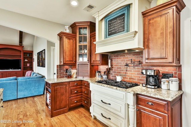 kitchen featuring light wood finished floors, black gas stovetop, visible vents, and light stone countertops