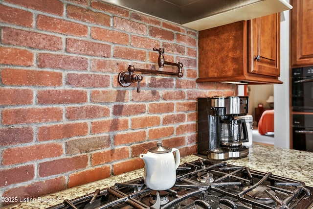 interior details with light stone counters, brown cabinetry, and oven