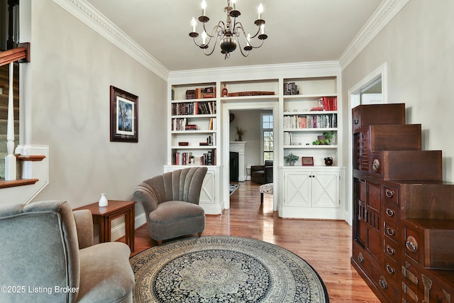 sitting room featuring a chandelier, crown molding, a fireplace, and wood finished floors