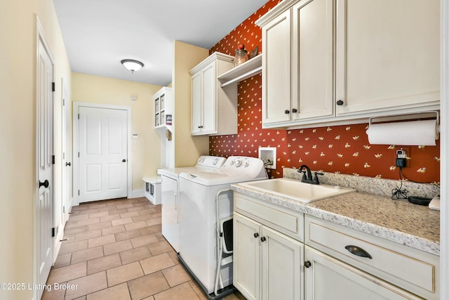 laundry room featuring wallpapered walls, cabinet space, baseboards, independent washer and dryer, and a sink