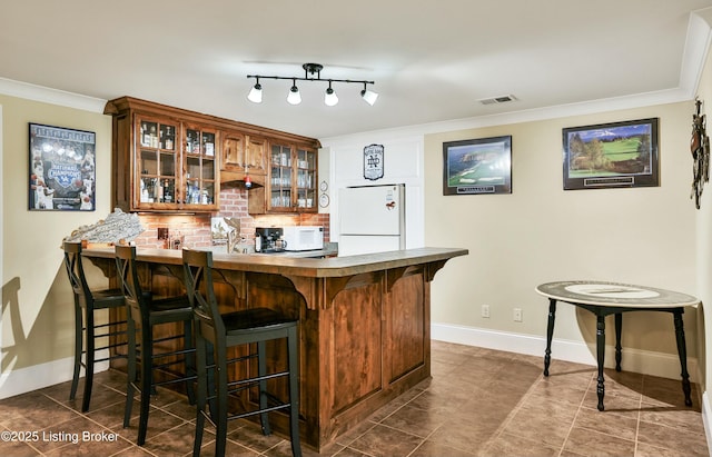 bar with crown molding, visible vents, decorative backsplash, baseboards, and fridge