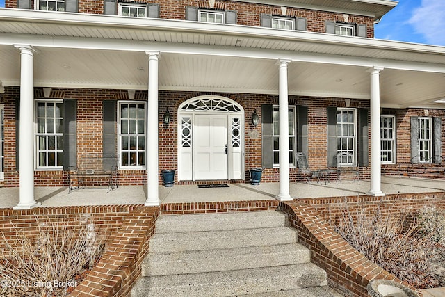 property entrance with a porch and brick siding