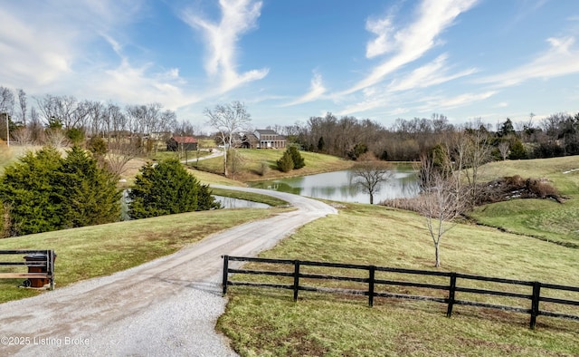 view of community featuring a water view, fence, and a lawn