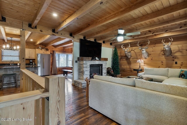 living area with wood ceiling, dark wood-style flooring, a fireplace, and beamed ceiling