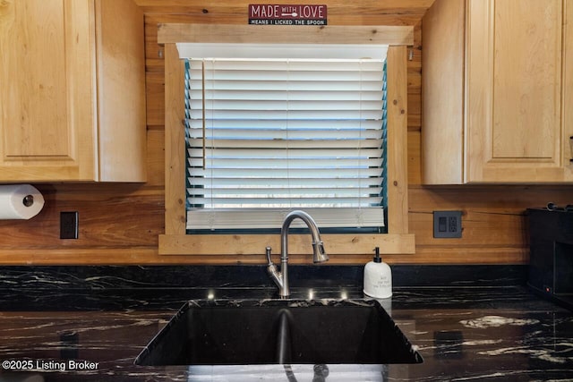 kitchen featuring dark countertops, light brown cabinets, and a sink