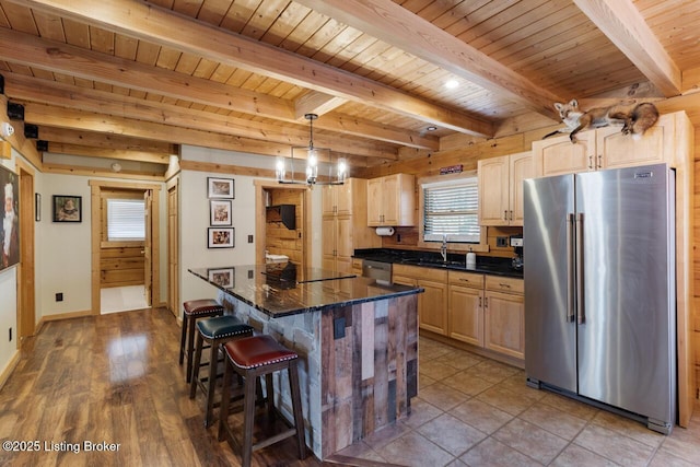 kitchen featuring wooden ceiling, appliances with stainless steel finishes, a breakfast bar area, light brown cabinets, and a sink