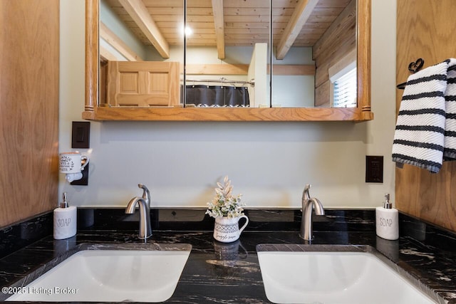 kitchen with wood ceiling, dark countertops, a sink, and beam ceiling