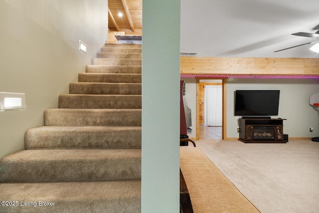 stairway featuring carpet floors, a fireplace, visible vents, and a ceiling fan