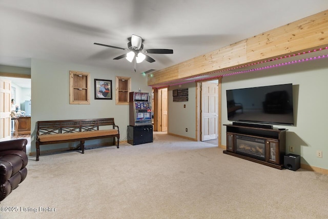 living room featuring carpet floors, visible vents, a ceiling fan, a glass covered fireplace, and baseboards