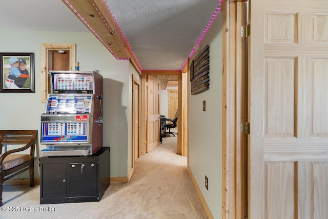 corridor with a textured ceiling, carpet floors, and baseboards