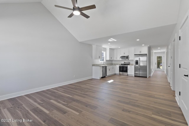 unfurnished living room featuring recessed lighting, plenty of natural light, dark wood finished floors, and baseboards