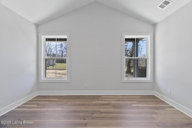 unfurnished room with a wealth of natural light, visible vents, and wood finished floors