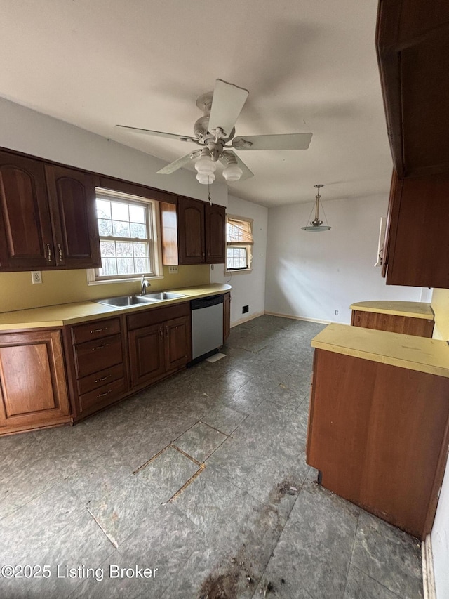 kitchen featuring light countertops, a ceiling fan, a sink, dishwasher, and baseboards