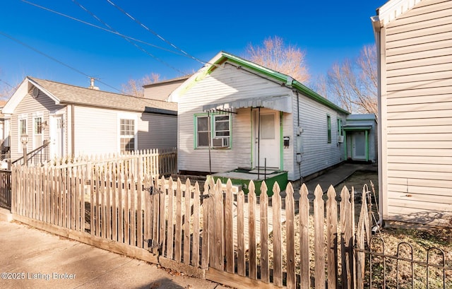 shotgun-style home featuring a fenced front yard and cooling unit