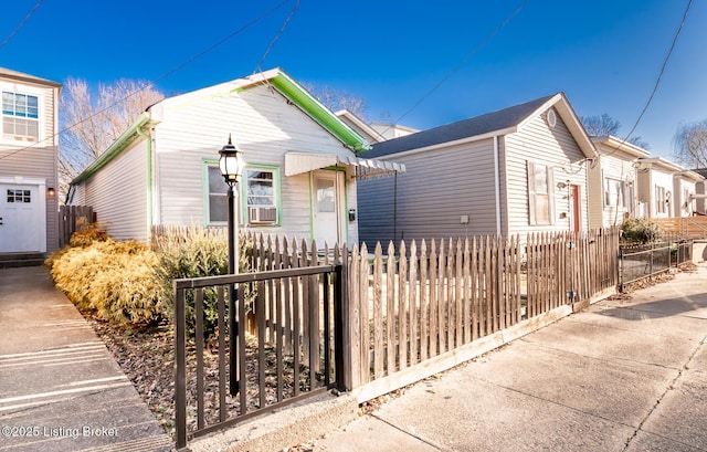 shotgun-style home with a fenced front yard and cooling unit