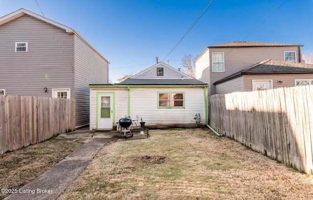 rear view of house with a fenced backyard and a lawn