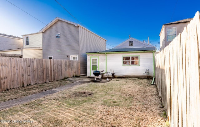 rear view of property featuring a fenced backyard and a lawn